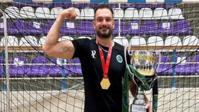 Milli hentbolcu Cem Denli'nin sağ kolunu sıkarak boynundaki madalya ve sol elinde tuttuğu kupayla verdiği fotoğraf pozu.