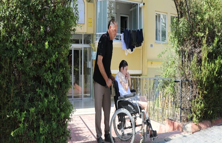 Görselde Adalet Erciyes, engelli kızı Merve'yi tekerlekli sandalye ile sokakta gezdiriyor.
