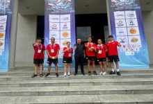 Türkiye Özel Sporcular Spor Federasyonu Başkanı Birol Aydın, spor salonu önünde milli sporcularla birlikte poz veriyor.