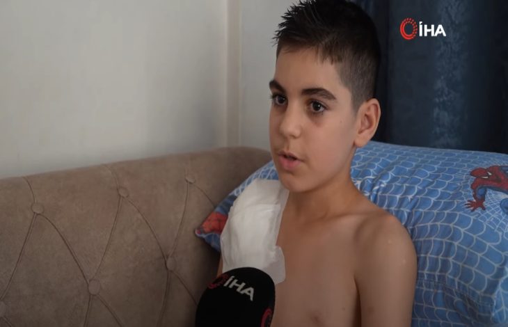 Köpeğin saldırısına uğrayan Yunus Aksoy'un sağ kolu pansumanlı olarak İHA mikronuna açıklama yapıyor. Görselin sağ üst köşesinde İHA logosu yer alıyor.