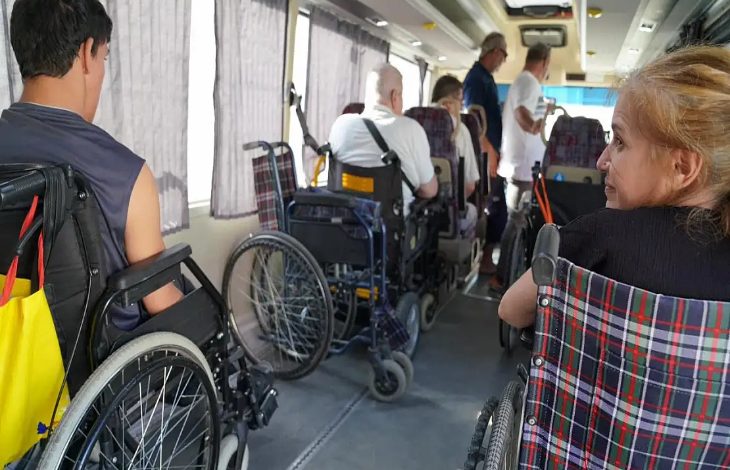 Görselde bir pikap tarzı arabanın içerisinde tekerlekli sandalye ve akülü tekerlekli sandalye kullanan engelli bireyler ve ailelerinin yer aldığı görülmektedir.