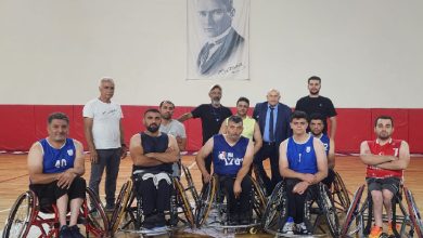 Görselde, bir spor salonunda tekerlekli sandalyedeki basketbol oyuncuları ve ayakta duran kişiler toplu halde poz veriyor. Oyuncuların üzerinde mavi ve kırmızı formalar var. Arka planda Atatürk portresi asılı. Grup, yeni sezon öncesi takım pozu verir gibi kameraya bakıyor.
