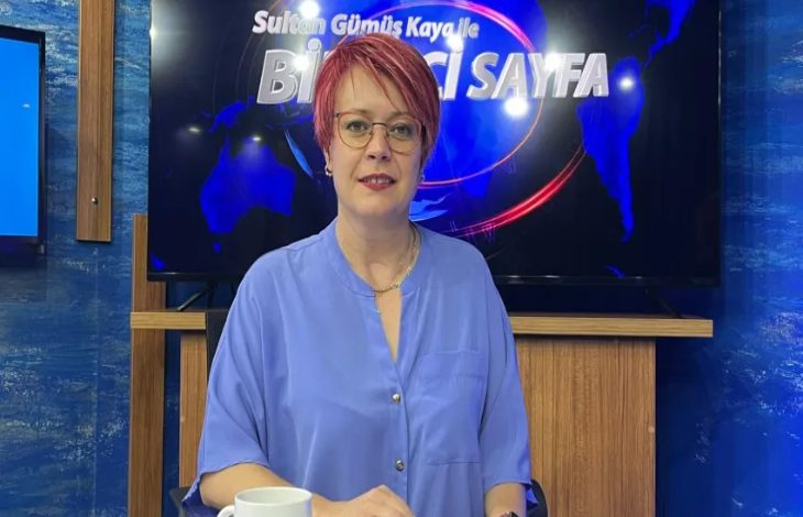 Görselde kısa saçlı, gözlüklü ve açık mavi gömlek giymiş bir kadın stüdyo ortamında oturuyor. Arkasında “Sultan Gümüş Kayalı ile Birinci Sayfa” yazısının yer aldığı bir ekran var. Masada beyaz bir fincan bulunuyor.