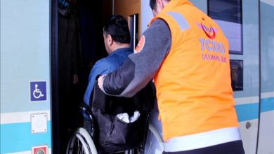 Görselde, turuncu yelekli bir TCDD personeli, tekerlekli sandalyedeki bir yolcuyu trene bindirmeye yardımcı oluyor. Yan tarafta engelli erişim simgesi yer alıyor. Kare, engelli bireyler için ulaşımda sunulan desteği yansıtıyor.