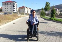 Engelli Engin Demir, sokakta akülü sandalye kullanıyor.