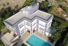 Üç katlı, terası ve havuzlu özel bakım merkezinin kuş bakışı fotoğrafı.