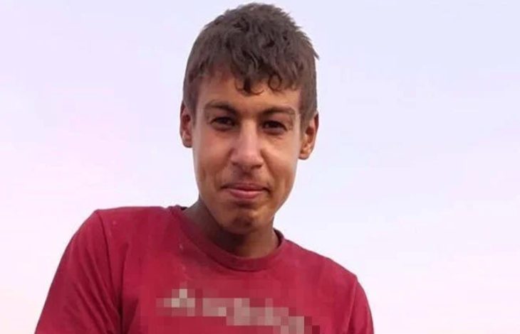 Görselde, açık havada çekilmiş bir fotoğraf yer alıyor. Kısa saçlı, genç bir erkek çocuğu Halil Abay kırmızı tişört giymiş şekilde kameraya doğru hafif bir gülümsemeyle bakıyor. Arka plan sade, açık gökyüzü görünüyor. Tişörtteki yazı bulanıklaştırılmış.