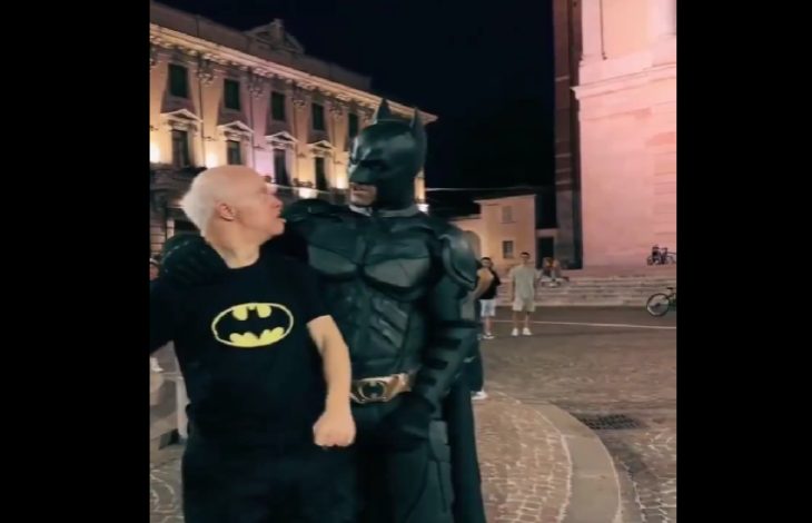 Görselde gece saatlerinde, tarihi bir şehir meydanında çekilmiş duygusal bir an yer alıyor. Siyah Batman tişörtü giymiş, beyaz saçlı Down sendromlu bir birey, tam teçhizatlı Batman kostümü giymiş bir kişiyle yan yana duruyor. Batman, kolunu sevgiyle bireyin omzuna dolamış; ikisi de birbirine sıcak ve samimi bir şekilde bakıyor. Arka planda tarihi yapılar ve birkaç kişi görülüyor. Bu kare, özel bir sürprizin ve dokunaklı bir karşılaşmanın etkileyici anını yansıtıyor.