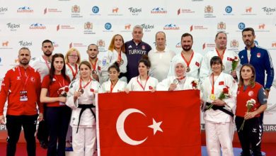 Milli Para Judocularımız, teknik heyetle birlikte Türk Bayrağı tutarak poz veriyor.