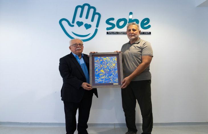 SOBE Vakfı Başkanı Mustafa Ak, Mehmet Ali Atiker’e otizmli bir öğrencinin hazırladığı ebru tablosunu hediye ediyor