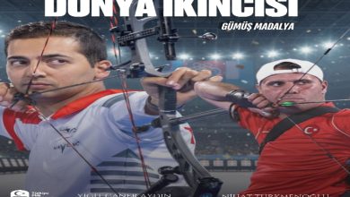 Görselde okçuluk yapan iki sporcu yer alıyor. Üst kısımda büyük harflerle “DÜNYA İKİNCİSİ – GÜMÜŞ MADALYA” yazıyor. Sol altta Türkiye Bedensel Engelliler Spor Federasyonu’nun logosu bulunuyor. Sporcuların isimleri de altta belirtilmiş: Yiğit Caner Aydın ve Nihat Türkmenoğlu. Arka planda bir spor salonu atmosferi görünüyor.