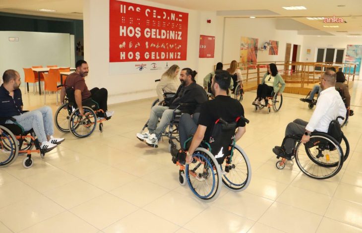 Eğitim salonunda tekerlekli sandalye kullanan belediye personelleri bulunuyor.