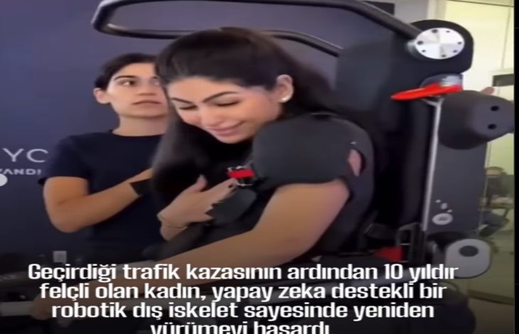 Bir kadın, yapay zekâ destekli robotik bir dış iskelet yardımıyla ayakta duruyor. Yanında ona destek olan bir görevli bulunuyor. Kadın gülümseyerek duygusal bir an yaşıyor. Alt kısımda, kazadan sonra 10 yıl boyunca felçli kaldığı ve bu teknolojiyle yeniden yürümeyi başardığı yazılı.