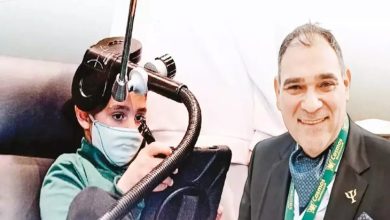 Görselde iki kişi yer alıyor. Solda, yüzünde maske olan bir çocuk başında özel bir cihazla tablet kullanıyor. Sağda ise takım elbiseli, boynunda kimlik kartı asılı gülümseyen bir yetişkin bulunuyor.