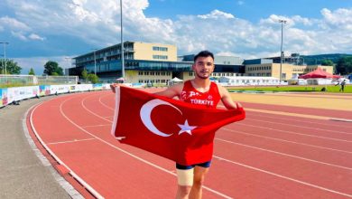 Milli sporcumuz Abdullah Ilgaz, tartan pistte Türk Bayrağı tutarak poz veriyor.