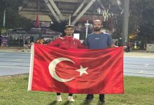 Milli Atlet Mehmet Emin Eğilmez antrenörü ile birlikte Türk Bayrağını tutarak poz veriyor.