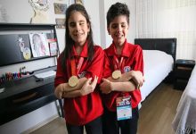 Görme engelli Ömer ve Emel Erva Koç kardeşler, ayakta durarak madalyalarıyla poz veriyorlar.