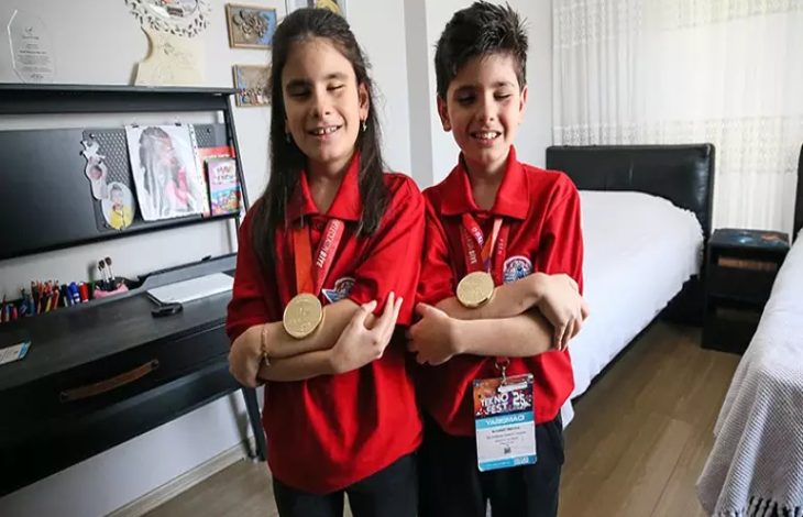 Görme engelli Ömer ve Emel Erva Koç kardeşler, ayakta durarak madalyalarıyla poz veriyorlar.