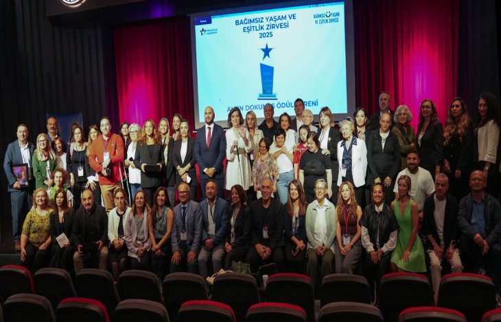 Kalabalık bir grup, sahne önünde toplu fotoğraf çektiriyor. Arkada “Bağımsız Yaşam ve Eşitlik Zirvesi 2025 – Altın Dokunuş Ödül Töreni” yazılı bir ekran yer alıyor. Katılımcılar sahnede gülümseyerek poz veriyor.