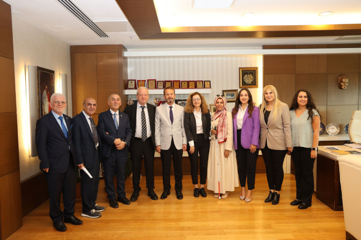 Makam odasında Anayasa Mahkemesi Üyesi Kenan Yaşar ve Türkiye Barolar Birliği Engelli Hakları Komisyonu Üyeleri ayakta yan yana durarak poz veriyor.