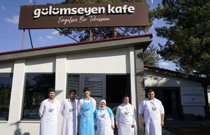 Gülümseyen Kafe önünde özel gereksinimli personeller poz veriyor.