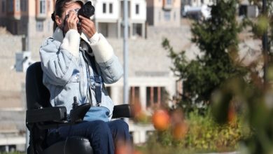 Dilek Çimen, tekerlekli sandalyesinde bulunarak fotoğraf çekiyor.