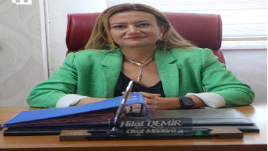 Yeşil ceketi ve kararlı duruşuyla okul müdürü Hilal Demir, bordo koltuğunda otururken önündeki isimlik, klasörler ve düzenli masa düzeni onun disiplinli, güçlü ve ilham veren bir eğitimci olduğunu tek karede hissettiriyor.