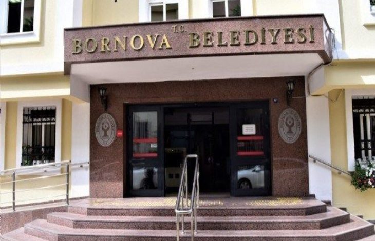 Bir binanın girişinde “T.C. Bornova Belediyesi” tabelesi yer alıyor. Girişte merdivenler, rampalar ve belediye amblemleri görülüyor.