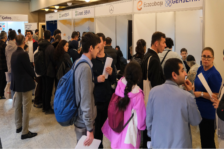 Katılımcılar, Garanti BBVA, Mercedes, Eczacıbaşı ve Gensenta gibi firmaların stantlarının bulunduğu fuar alanında görüşmeler yapıyor. Ellerinde belgelerle sırada bekleyen ve bilgi alan kişiler dikkat çekiyor.