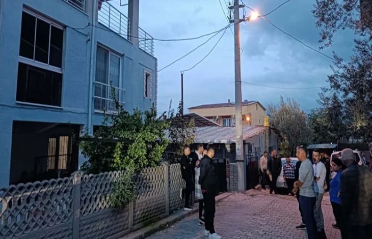 Akşam saatlerinde çekilmiş bir sokak görüntüsü var. Bir apartmanın önü ve dar bir ara sokak boyunca toplanmış insanlar görülüyor. Bazıları kapının önünde bekliyor, bazıları karşı tarafta ayakta durup konuşuyor. Sokak lambası yanıyor, ortamda merak ve tedirginlik hissi hâkim.