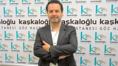 Görselde bir göz hastanesinin tanıtım panosu önünde duran Op. Dr. Sedat Selim görülüyor. Üzerinde koyu renk bir ceket ve beyaz gömlek var. Kollarını önde birleştirerek poz vermiş. Arka planda tekrarlayan “Kaşkaloğlu Göz Hastanesi” yazıları ve göz logosu yer alıyor. Ortam profesyonel ve sağlık kurumuna ait bir tanıtım havası taşıyor.