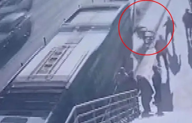 Görselde güvenlik kamerası görüntüsü tarzında, metrobüs durağı yanında geçen bir an görülüyor. Sağ üst tarafta kırmızı bir daire içine alınmış bölümde tekerlekli sandalyedeki bir kişinin metrobüs yoluna doğru düştüğü ya da kaydığı an yer alıyor. Çevrede birkaç yolcunun gölgeleri ve merdiven çıkışı görünüyor. Sahne, yoğun trafiğin olduğu bir hatta yaşanan ciddi bir kazayı yansıtıyor.