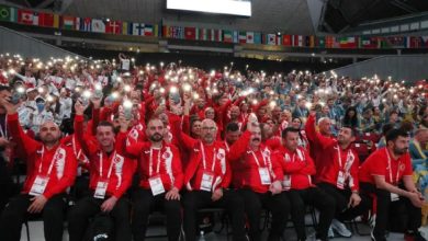 Tokyo 2025 İşitme Engelliler Yaz Olimpiyatları'na katılan sporcular, teknik kadro ile yetkililer telefon ışıklarını açarak poz veriyorlar.