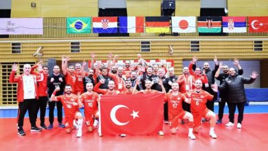 İşitme Engelliler A Milli Hentbol Takımı ve teknik kadro Türk Bayrağı tutarak poz veriyor.