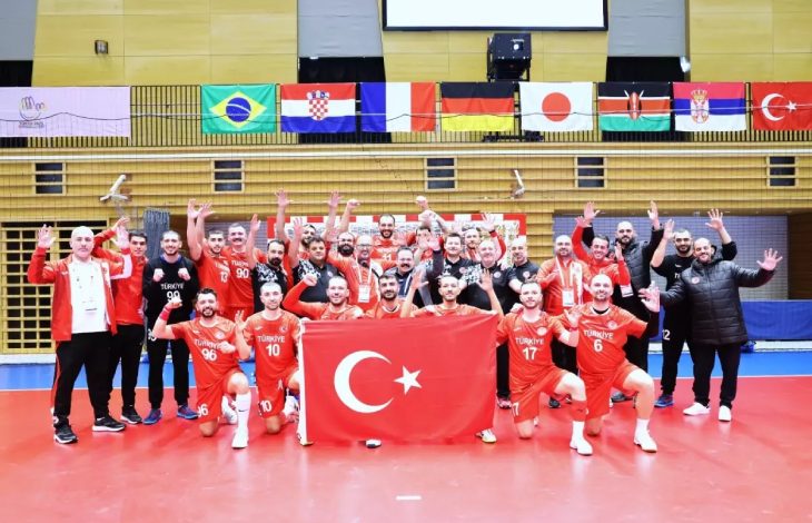 İşitme Engelliler A Milli Hentbol Takımı ve teknik kadro Türk Bayrağı tutarak poz veriyor.