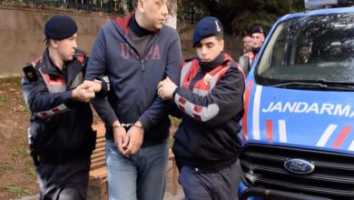 Ellerinde kelepçe bulunan okul müdürünü iki jandarma personeli götürüyor.