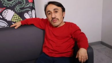 İçerik Üreticisi Rıdvan Çelik kırmızı kazak giyinmiş ve koltukta oturup poz veriyor.