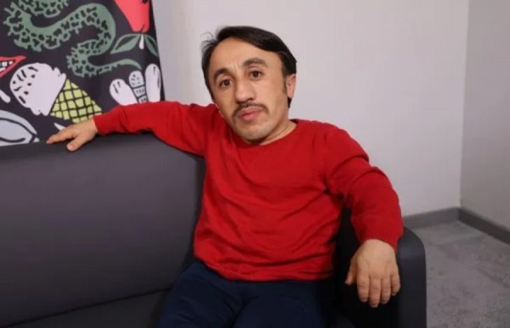 İçerik Üreticisi Rıdvan Çelik kırmızı kazak giyinmiş ve koltukta oturup poz veriyor.