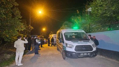 Sokakta olay yeri inceleme, cenaze nakil aracı park halinde ve sokak sakinleri ayakta bulunuyor.