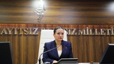 Antalya Büyükşehir Belediye Başkan Vekili Büşra Özdemir makam kürsüsünde oturuyor ve önünde mikrofon bulunuyor.