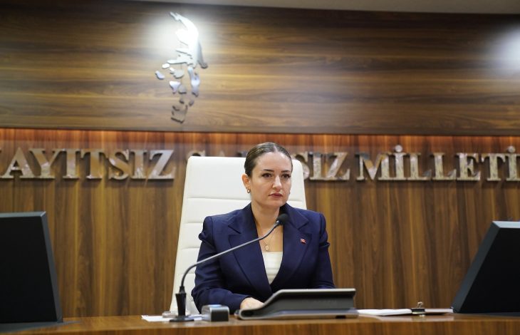 Antalya Büyükşehir Belediye Başkan Vekili Büşra Özdemir makam kürsüsünde oturuyor ve önünde mikrofon bulunuyor.