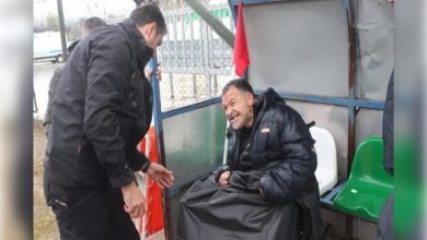 Tekerlekli sandalyesiyle saha kulübesinde bulunan engelli taraftar Nevzat Kahyaoğlu ile yağmurluğunu örten İlçe Emniyet Müdürlüğü Başkomiseri Ramazan Kalkan iletişim kuruyor.