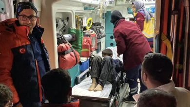 Görselde, bir ambulansın içinde sedyeye yatırılmış bir çocuğa sağlık ekipleri müdahale ediyor. Etrafında ambulans personeli ve görevliler bulunuyor; ortam acil müdahale durumunu yansıtıyor.