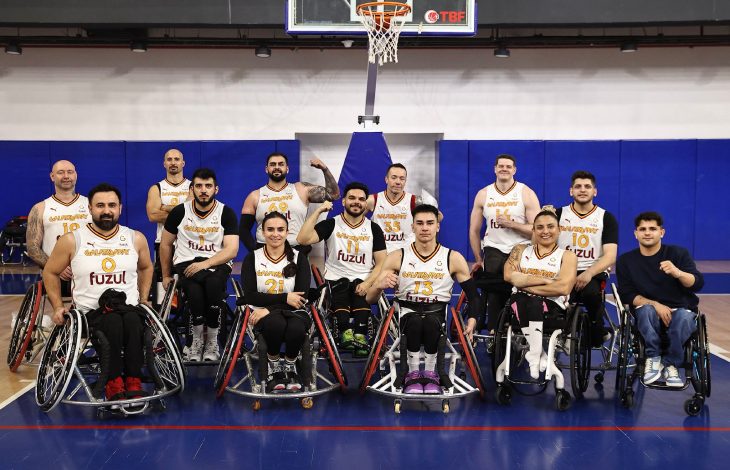 Galatasaray Fuzul Tekerlekli Sandalye Basketbol Takımı pota önünde poz veriyor.