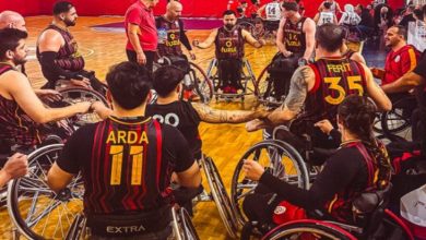 Galatasaray Fuzul Tekerlekli Sandalye Basketbol Takımı oyuncuları maç öncesi sahada halka halinde toplantı yaparken.