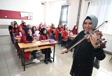 Görme engelli öğretmen Zeynep Temirci, sıralarda oturan öğrencilerine keman çalıyor.