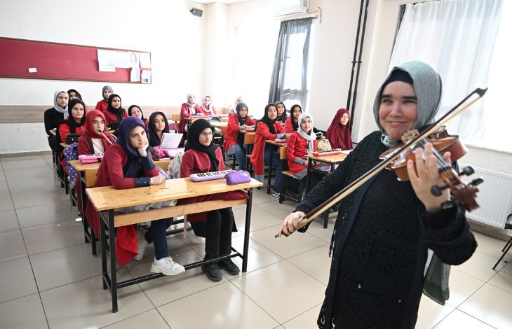 Görme engelli öğretmen Zeynep Temirci, sıralarda oturan öğrencilerine keman çalıyor.