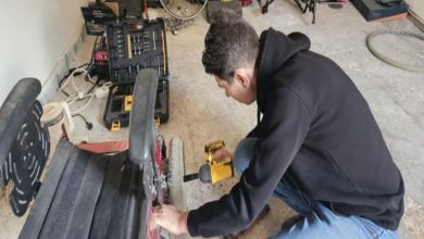 Hakkı Avcı, akülü sandalyenin tekerleğini onarıyor.