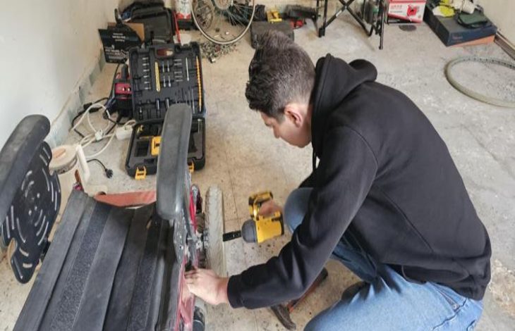 Hakkı Avcı, akülü sandalyenin tekerleğini onarıyor.