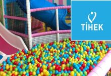 Rengârenk toplarla dolu bir çocuk oyun havuzu ve kaydıraklı bir oyun alanı görülüyor. Sağ üst köşede mavi zeminde “TİHEK” logosu yer alıyor. Görsel, bir çocuk oyun alanı ile kurum logosunun birlikte sunulduğu bir haber görseli niteliğinde.